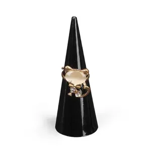 Golden cat-shaped ring with pink opal face and bow tie detail on a black display stand