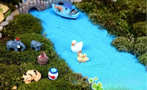 Macro detail of miniature resin animals and garden accessories on faux moss and blue sand