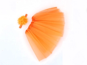 Detailed flat lay of an orange chiffon tutu skirt and matching floral headband for infants