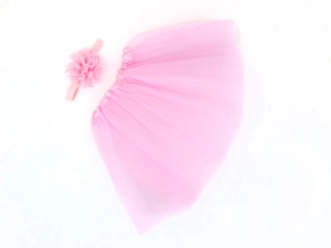 Flat lay of pink tulle tutu skirt and matching floral headband set for infant photography