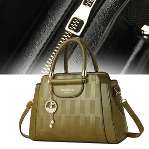 Detail of green textured leather handbag with gold hardware and woven pattern details