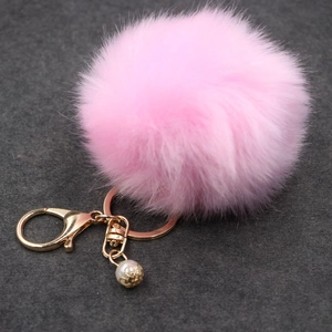 Dettaglio portachiavi in ecopelliccia rosa con anello dorato e ciondolo a perla elegante