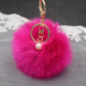 Dettaglio portachiavi a pompon in pelliccia sintetica rosso rosa con anello dorato
