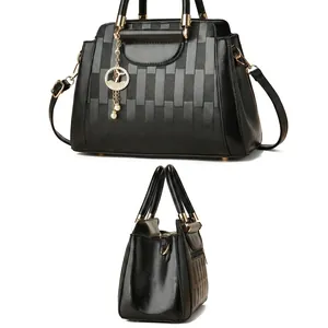 Detail of black leather bucket bag featuring vertical quilt texture and golden pearl charm