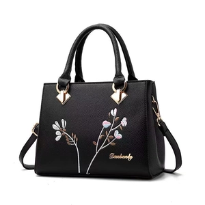 Classic black litchi grain shoulder bag with elegant floral embroidery and top handles