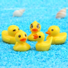 Detailed macro view of five cute yellow duck fridge magnets on a blue sandy beach background
