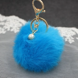 Portachiavi con pompon in ecopelliccia blu, gancio dorato e perla su pizzo bianco