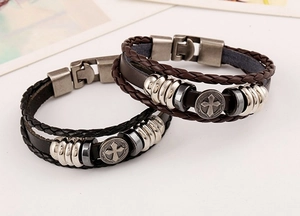 Close-up of woven leather bracelets in black and brown with cross pendant and metal beads
