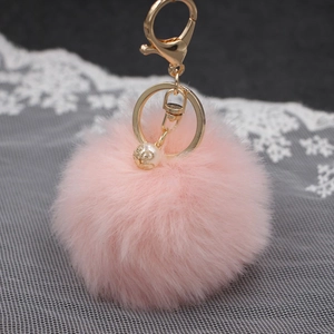 Dettaglio del portachiavi pompon in pelliccia sintetica rosa con gancio dorato