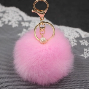Dettaglio portachiavi in pelliccia sintetica rosa con anello oro e perla elegante