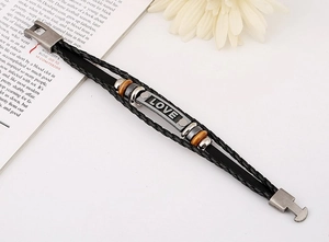 Detail of black woven leather bracelet featuring a LOVE engraved plate and wood beads