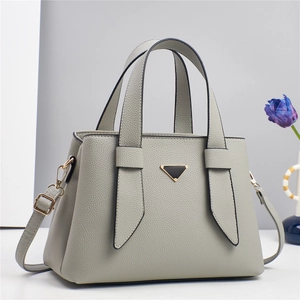 Detail of light grey pebbled leather handbag featuring triangular metal hardware decoration