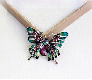 Macro detail of enamel butterfly brooch with colorful gradients and faceted gemstones