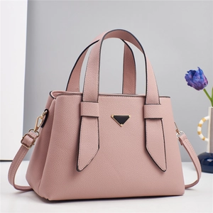 Detailed view of pink lychee leather texture and metallic triangle logo on handbag
