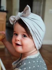 Detail of baby turban hat in light gray featuring a large decorative bow knot design
