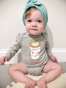Close-up of baby bodysuit with 'I LOVE YOU A Latte' print and mint green headband