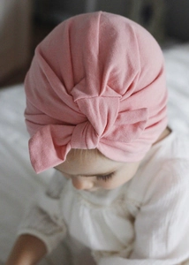 Close-up of pink baby turban hat with bow knot detail on soft knitted fabric