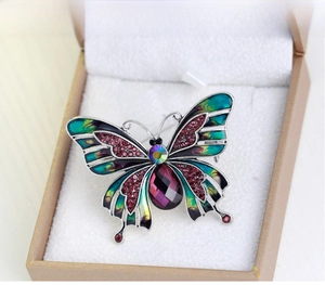 Detail of vintage butterfly brooch with green enamel wings and purple teardrop stone
