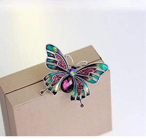 Macro shot of butterfly brooch with purple gemstone and blue-green enamel detail