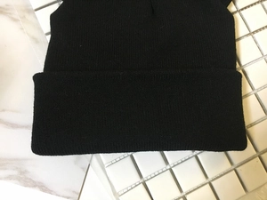 Detailed close-up of a black knitted beanie with cute cat ears showing fine woven texture
