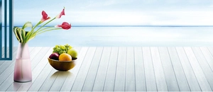 Pink frosted glass vase with calla lilies on a seaside terrace with fruit bowl