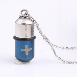 Detail of cross symbol on a silver and blue stainless steel capsule pendant necklace