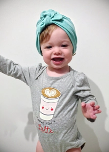 Close-up of gray cotton baby bodysuit with coffee heart print and mint green headband