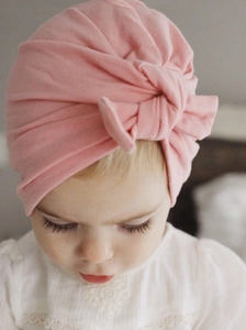 Close-up of soft pink baby turban hat featuring an elegant bow knot on the infant girl