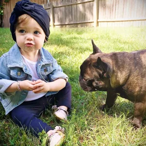 Infant turban in navy blue with a large bow shown on a baby in a garden setting