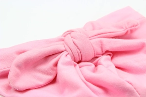 Detail of pink knitted baby hat with soft knotted bow design and premium fabric texture