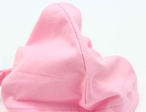 Close-up of pink cotton knit fabric texture and neat sewing on a baby turban hat