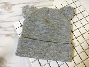 Detailed flat lay of a grey knit beanie featuring cute cat ears on a marble background
