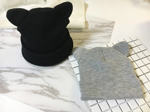 Flat lay view of knitted beanies featuring cute cat ear designs in black and grey colors
