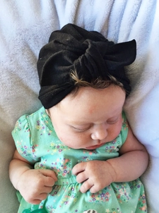 Detail of baby black knotted headband with soft cotton texture on blue plush background