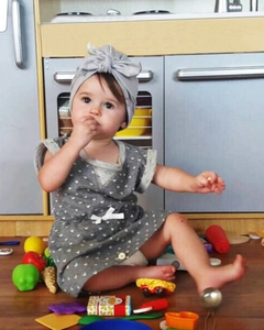 Detail of grey infant dress with heart prints and matching bow headband on wooden floor