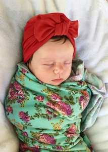 Close-up of red bow turban and floral swaddle blanket on a sleeping baby girl