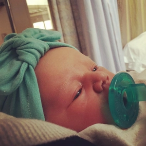 Detail of mint green baby headband with knot design and matching silicone pacifier set