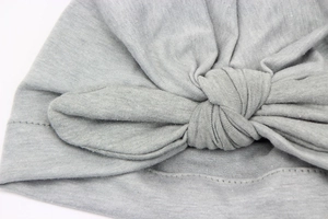 Macro shot of light gray knitted infant hat featuring detailed handmade knot craftsmanship
