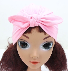 Front close-up of pink baby turban hat with a knotted bow design on mannequin head