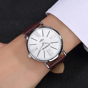 Classic silver quartz watch with Roman numerals and brown leather strap on wrist