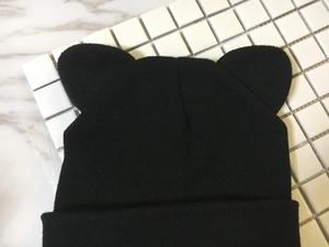 Close-up of black knitted beanie featuring cat ear design and detailed ribbed texture