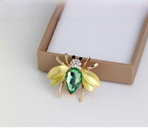 Detailed close-up of a bee-shaped brooch with green crystal and sparkling rhinestones