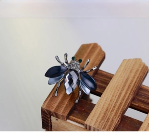 Detail of bee brooch with grey crystal wings and sparkling green emerald eyes