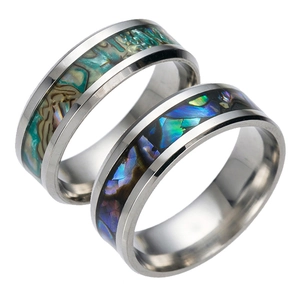 Close-up of titanium steel rings featuring green and purple abalone shell inlays