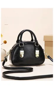 Detailed shot of a black semi-circular handbag with glossy wrinkled texture and gold hardware