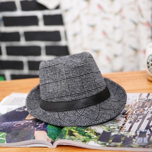 Dettaglio macro del cappello fedora grigio con fascia nera su tavolo di legno e rivista