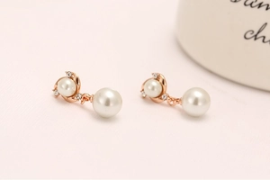 Macro detail of rose gold pearl earrings with sparkling white cubic zirconia accents