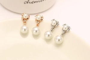 Detail of rose gold and silver rhinestone spiral earrings with elegant white pearls