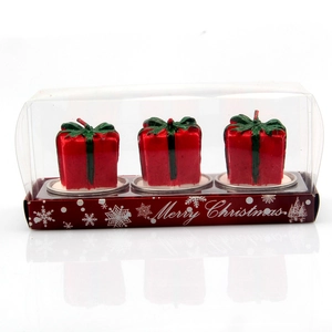 Three red gift-shaped Christmas candles with green bows in a Merry Christmas gift box