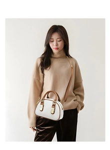 Detail of white and brown crossbody bag featuring gold hardware and adjustable strap